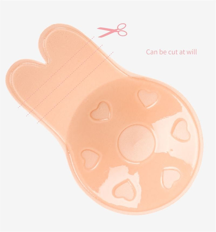 The Shapelux Lifting Pads for Invisible Breast Lift are beige, bunny-shaped adhesive pads with heart cutouts and a glossy finish, featuring dashed lines and a scissors icon to show they can be cut to size. Text: Can be cut at will.