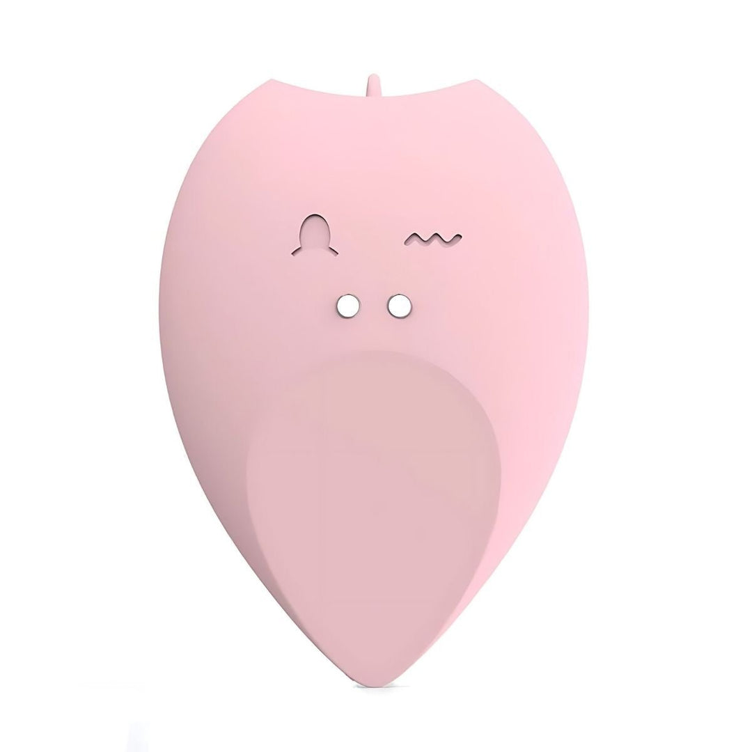 The Intimia Licking tear-drop vibrator is a pink, leaf-shaped clitoral stimulator with two small circular holes and engraved symbols, resembling a minimalist animal face, set against a white background.